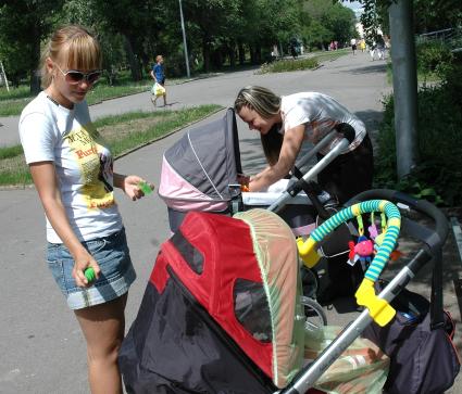 Мамаши закрывают москитными сетками детские коляски и обрабатывают противомоскитными средствами.