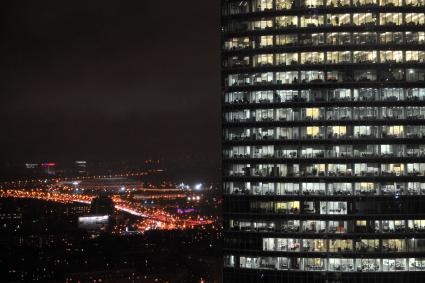 Небоскреб в `Москве-Сити` ночью с видом на стадион `Лужники`.