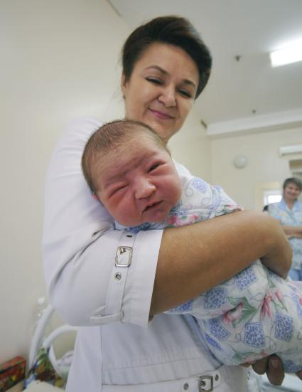 Врач держит на руках новорожденного ребенка.