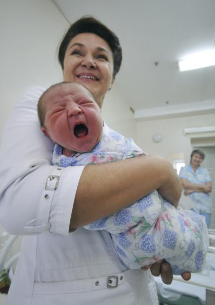 Врач держит на руках новорожденного ребенка.