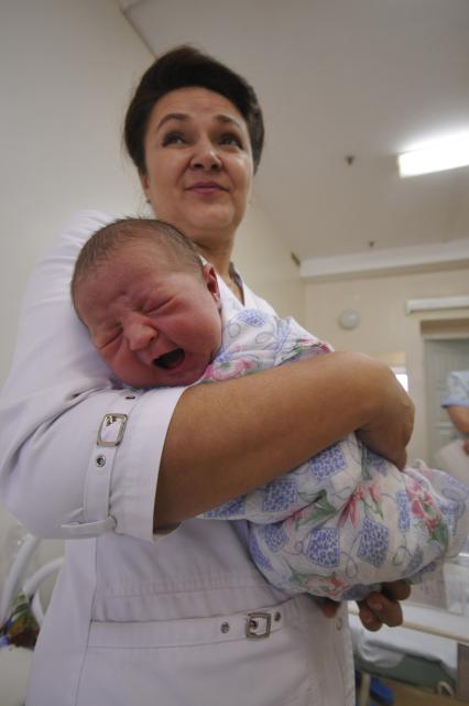 Врач держит на руках новорожденного ребенка.