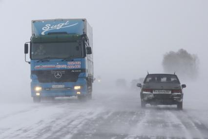 Автомобили на трассе в снегопад на Чуйском тракте.