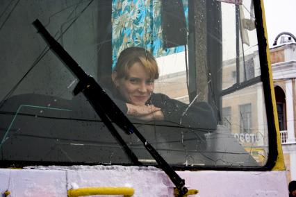 Девушка водитель трамвая улыбается.