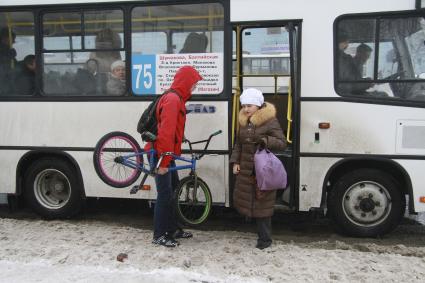 Парень с велосипедом садится в автобус.