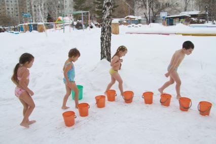Закаливание в детском саду зимой. На снимке: дети подбегают с ведеркам с водой.