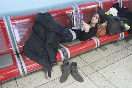 Девушка в ожидании своего рейса в аэропорту Барнаула читает журнал.