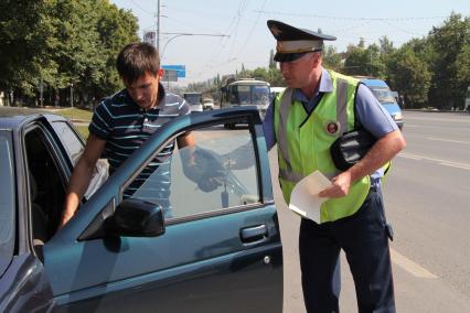 Сотрудник ДПС помогает водителю сдирать тонировку.