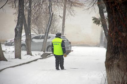 Дворник с лопатой под снегопадом.