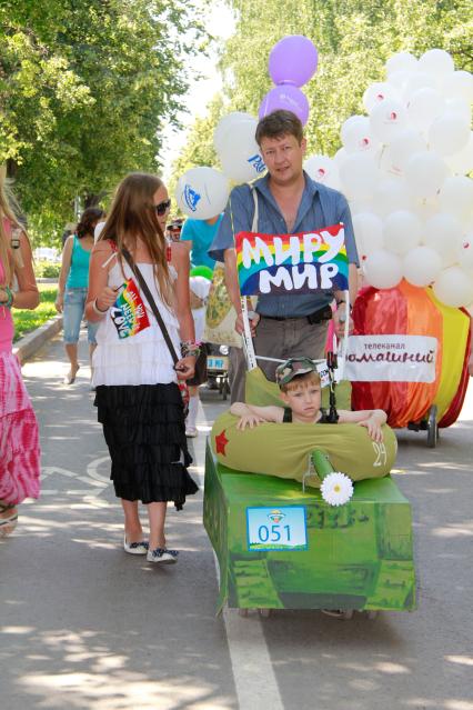 Парад детских колясок в Уфе. На снимке: родители с плакатами `миру мир` идут рядом с детской коляской стилизованной под танк.