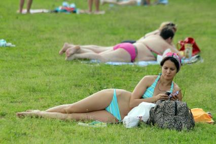 Девушка слушает музыку на пляже лежа на траве.