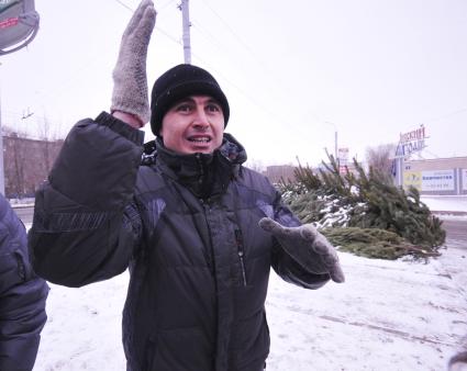 Елочный базар. На снимке: мужчина жестикулирует на фоне новогодних сосен.