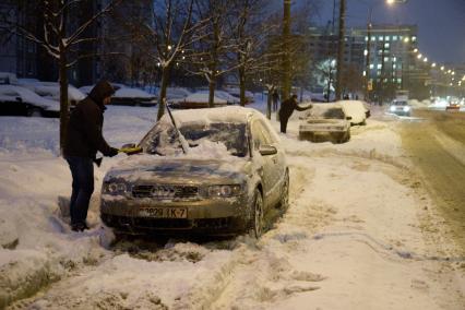 Минск. Зимний вечер. Автовладельцы счищают снег с машин.
