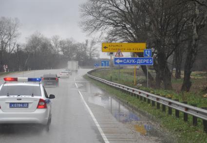 Полицейский автомобиль на дороге. На снимке: указатель `Крымск`.