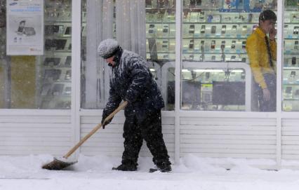 Уборка снега на городской улице. На снимке: дворник с лопатой.