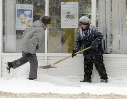 Уборка снега на городской улице. На снимке: дворник с лопатой.