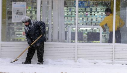 Уборка снега на городской улице. На снимке: дворник с лопатой.