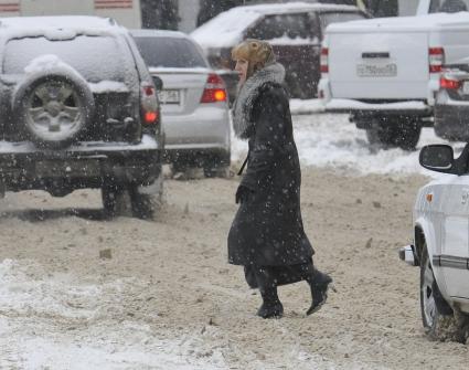 Зима в городе. На снимке: женщина и автомобили.