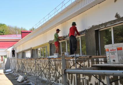 Рабочие ремонтируют фасад здания.