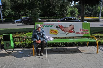 Старик просит милостыню сидя на скамейке с надписью: `Забери последнее!`