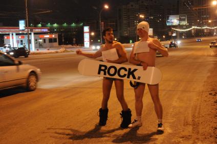 Новогодняя ночь. Парни без одежды прикрывая причинное место доской для сноуборда с надписью `Rock` ловят такси.