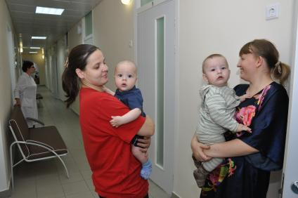 Мамы с детьми в коридоре больницы.
