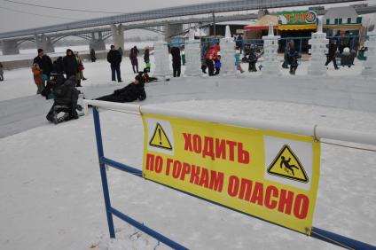 Заградительный плакат: `Ходить по горкам опасно` в ледовом городке.