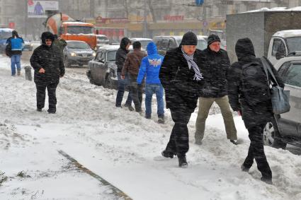 Прохожие на улице в сильный снегопад.