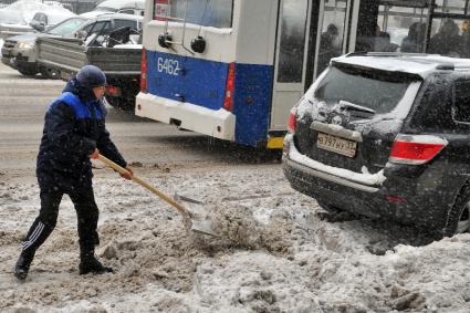 Дворник гастарбайтер чистит улицу от снега.