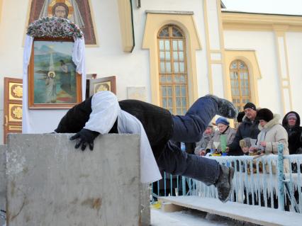 Раздача святой воды на Крещение в Новосибирске. Мужчина ныряет в чан со святой водой чтобы зачерпнуть воду.