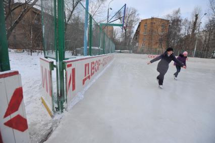 Хоккейная коробка во дворе дома. На снимке: девочки катаются на коньках