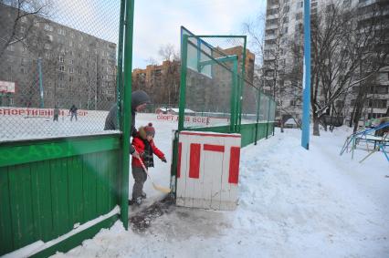 Хоккейная коробка во дворе дома. На снимке: мальчик на коньках с клюшкой в руках