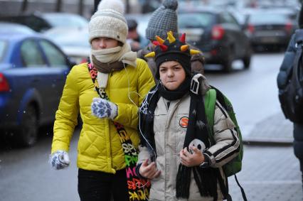 Мальчик с девочкой идут по улице и слушают музыку в наушниках