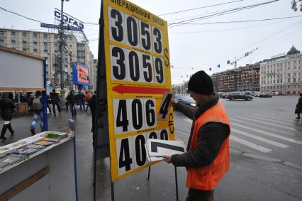 Мужчина меняет курс валюты на табло.