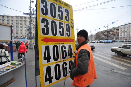 Мужчина меняет курс валюты на табло.