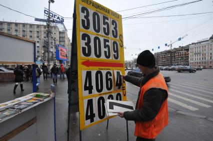 Мужчина меняет курс валюты на табло.