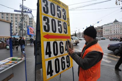 Мужчина меняет курс валюты на табло.