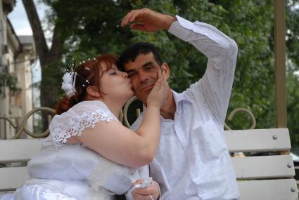 Русская невеста целует жениха кавказца.