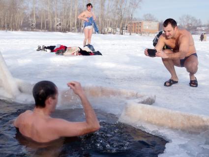 Крещенские купания на озере Шарташ в Екатеринбурге. На снимке: мужчина фотографирует как в проруби ныряет его друг.