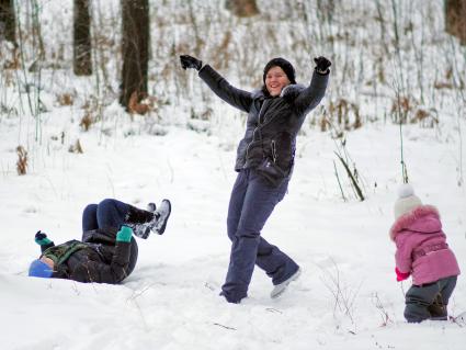 Женщина веселиться с двумя детьми в зимнем лесу.