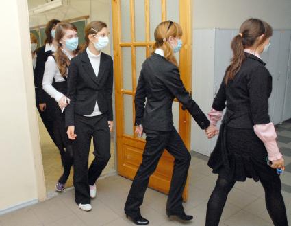 Школьники в медицинских повязках выходят из класса в коридор на перемену.