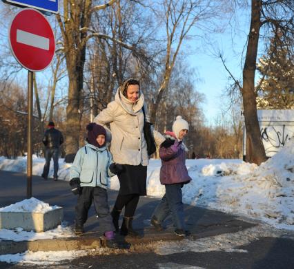 Женщина с детьми переходят дорогу.