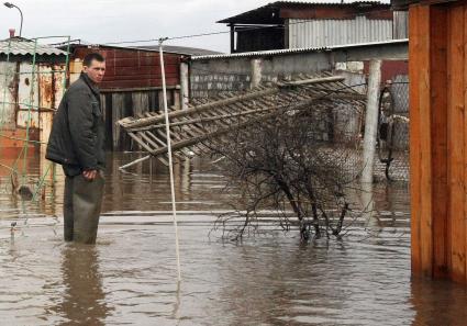 Весенним паводком затопило деревню в Самарской области. На снимке: мужчина с болотных сапогах на фоне затопленного участка.