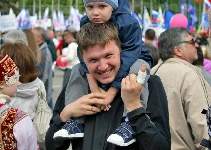 Празднование 1 мая в Самаре. На снимке: мужчина с ребенком на руках и перевязанным пальцем на фоне первомайской демонстрации.