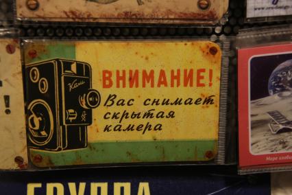 Магазин оригинальных подарков. На снимке: заламинированная табличка `Внимание! Вас снимает скрытая камера`.