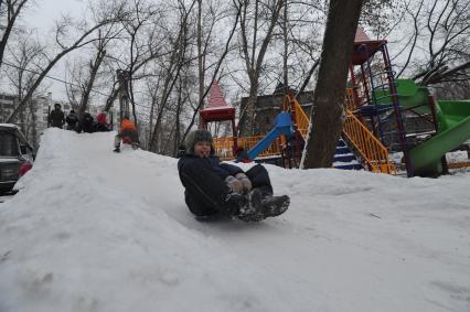 Мальчик с ледянкой на снежной горке.