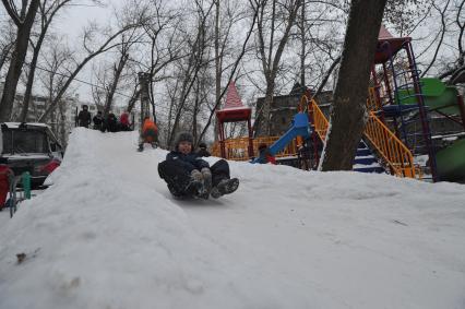 Мальчик с ледянкой на снежной горке.