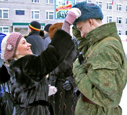 Девушка поправляет головной убор на солдате.