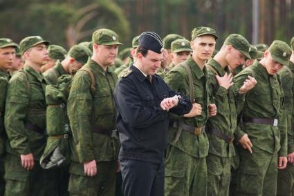 Офицер смотрит на часы перед отправкой призывников.