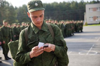 Призывник звонит по мобильному телефону перед строем солдат.