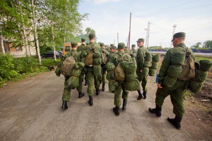 Солдаты с вещмешками идут по проселочной дороге.